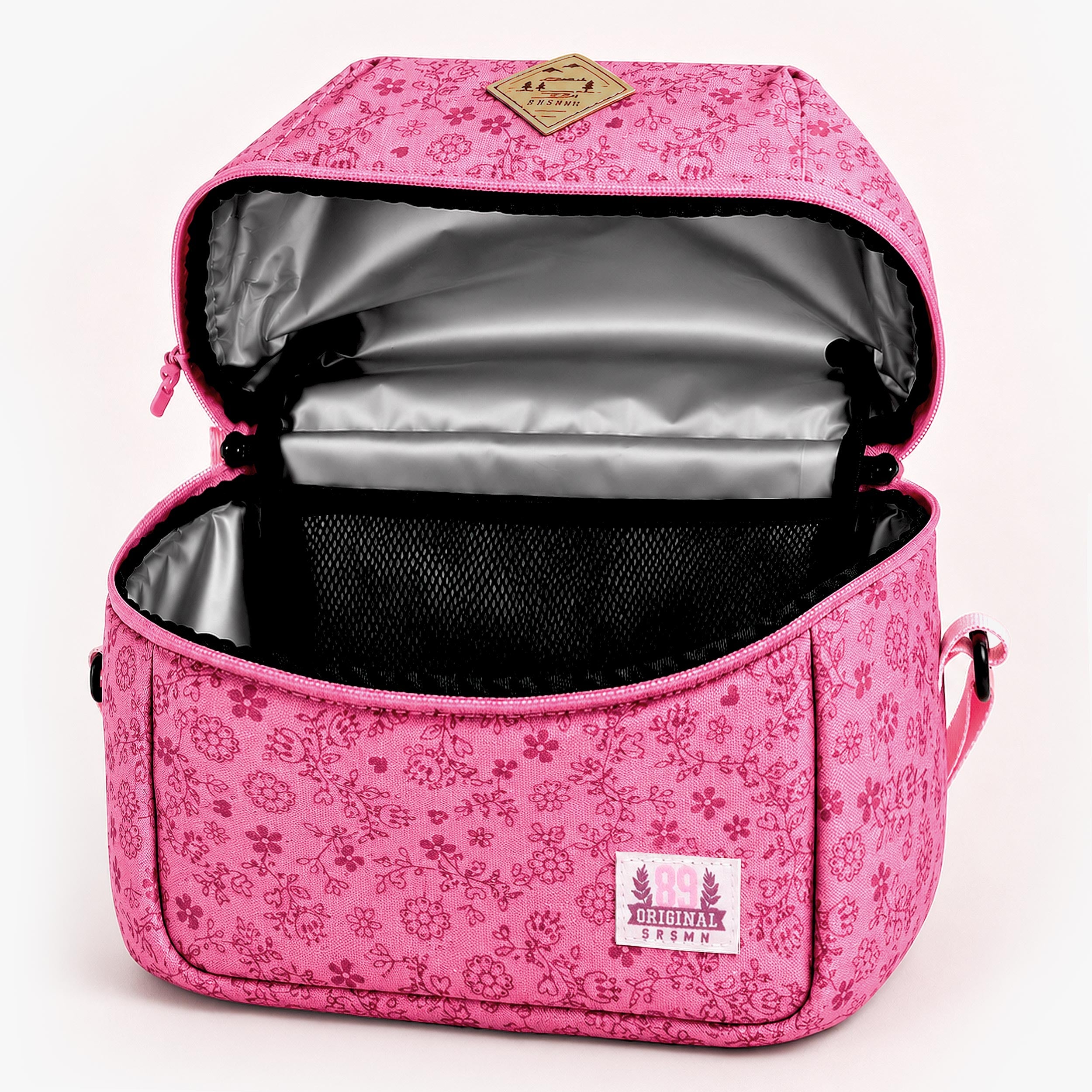 Intérieur d’un sac isotherme enfant rose à motif floral avec doublure thermique argentée et poche filet de rangement.