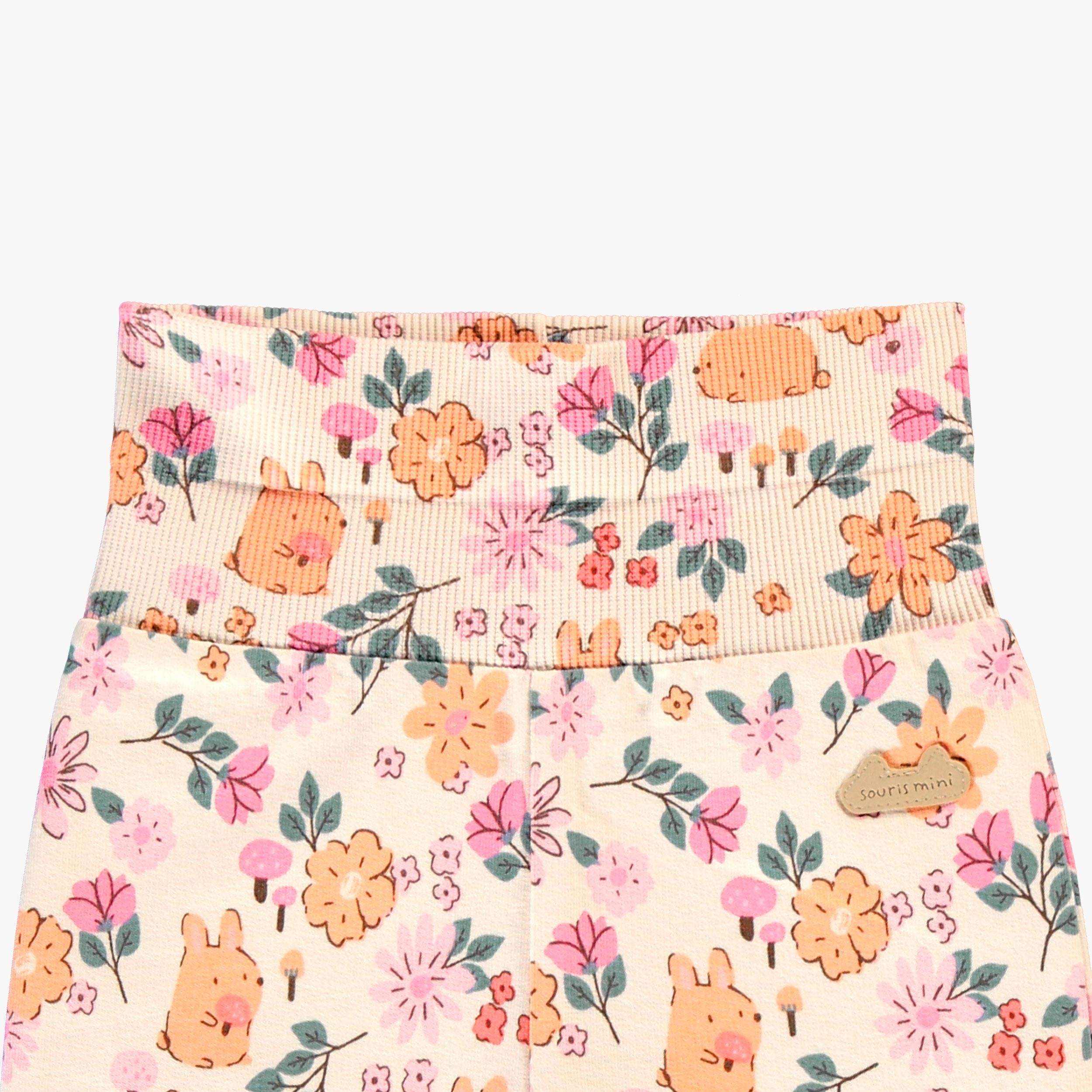 Gros plan sur la taille rabattable d’un legging bébé fille à imprimé floral et petits lapins, avec écusson décoratif.