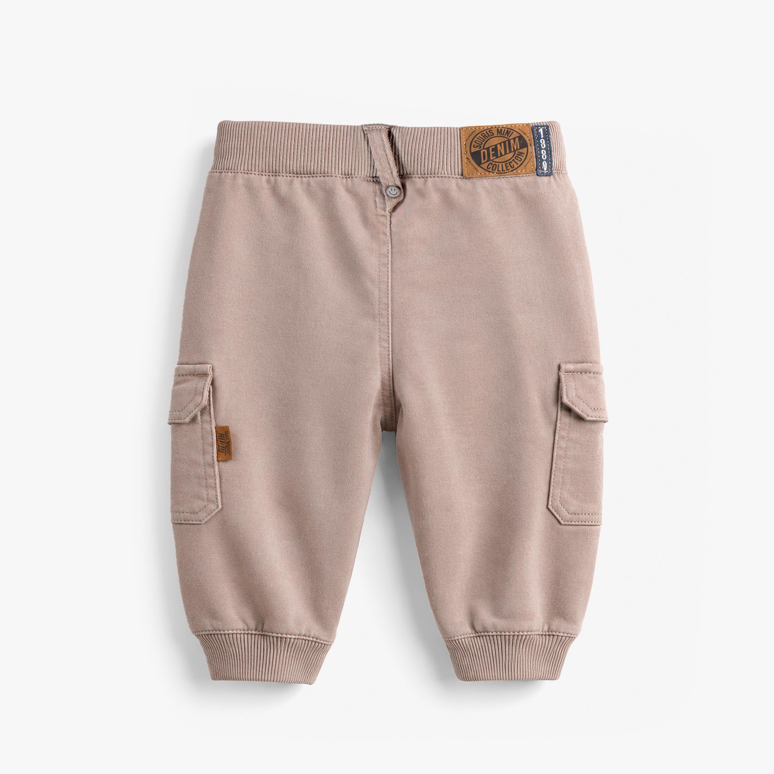 Vue arrière d’un pantalon jogger bébé beige sable avec poches cargo latérales et bords-côtes aux chevilles.
