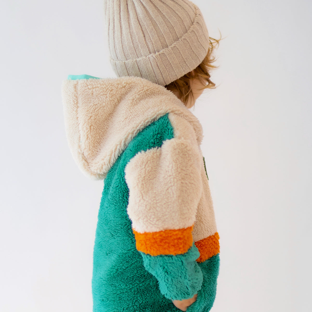 Enfant portant une polaire Souris Mini vert, beige et orange avec capuche, vue de dos.