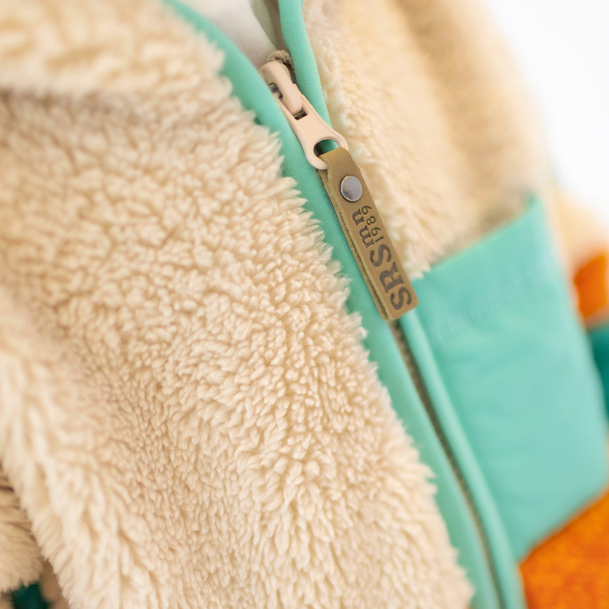Détail de la fermeture éclair d’une polaire enfant Souris Mini en tissu sherpa beige et vert.