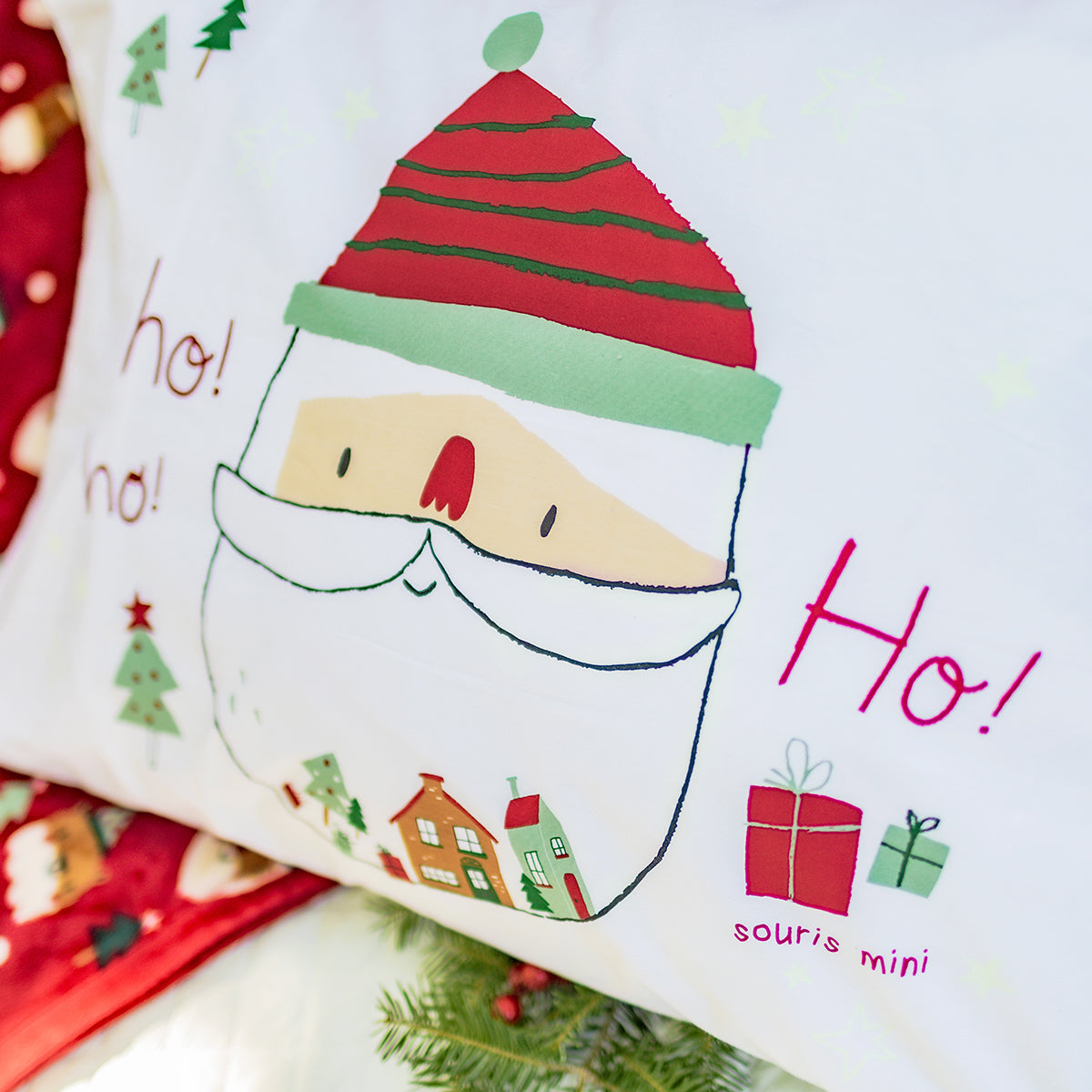 Verso du coussin de Noël Souris Mini avec illustration du Père Noël et inscription « Ho! Ho! Ho! », décor festif avec cadeaux, sapins et petites maisons.