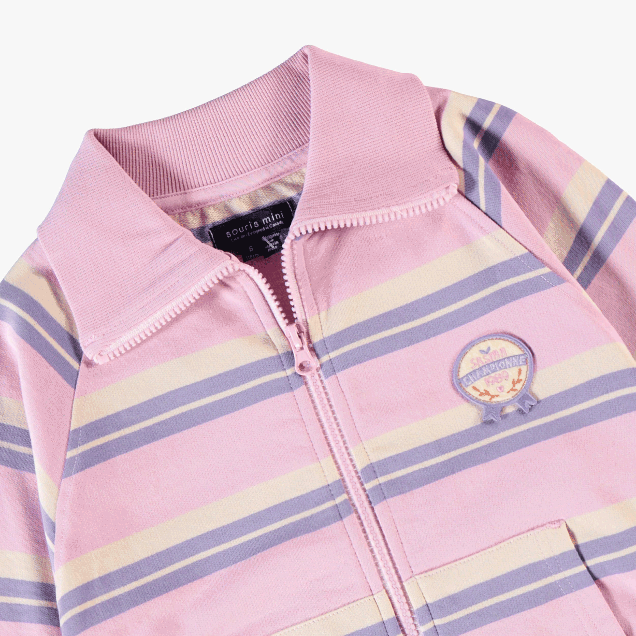 Vue détaillée du col montant, de la fermeture zippée et des rayures pastel d’une veste rose pour fille au style confortable et tendance.