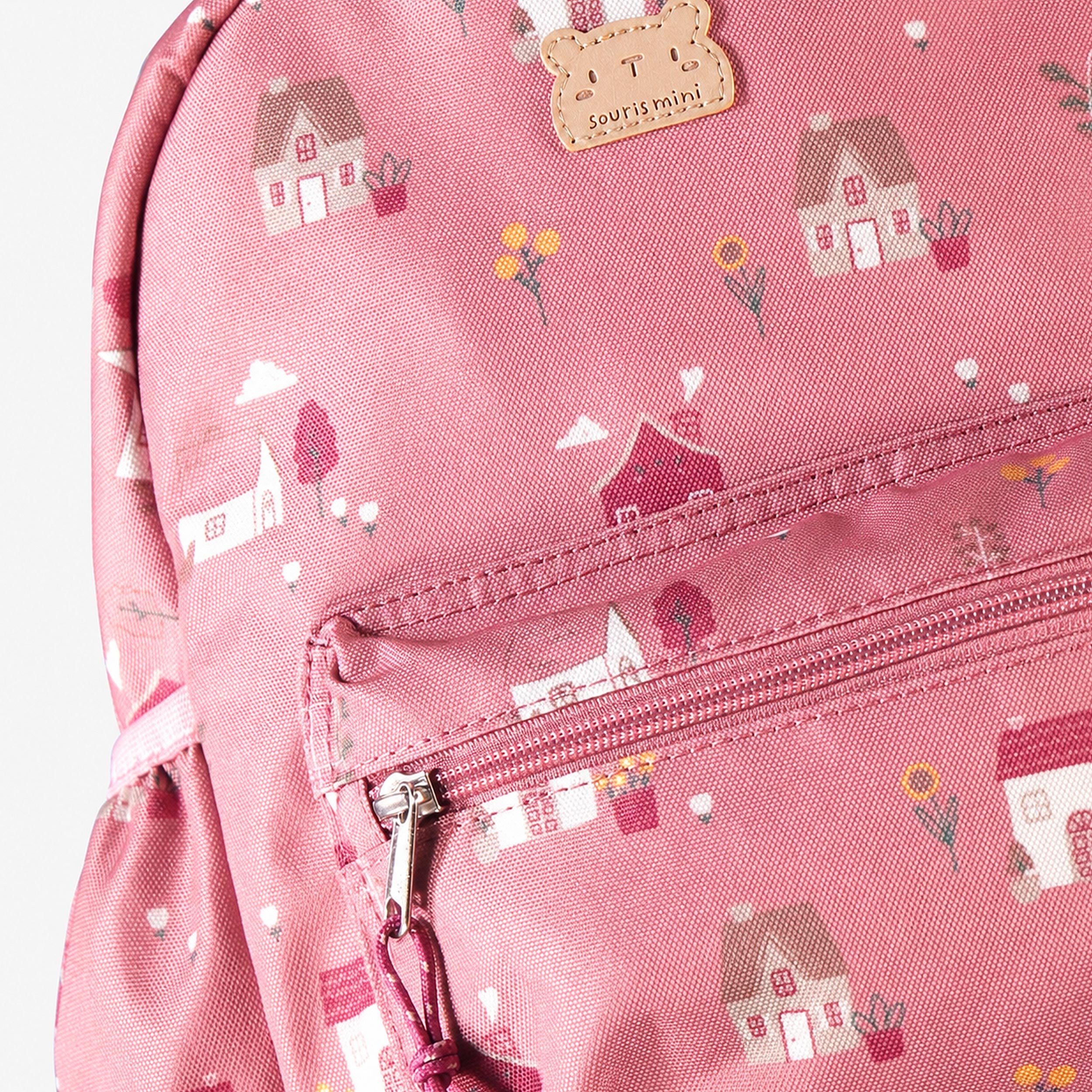 Zoom sur sac à dos enfant rose avec imprimé petites maisons et poche zippée