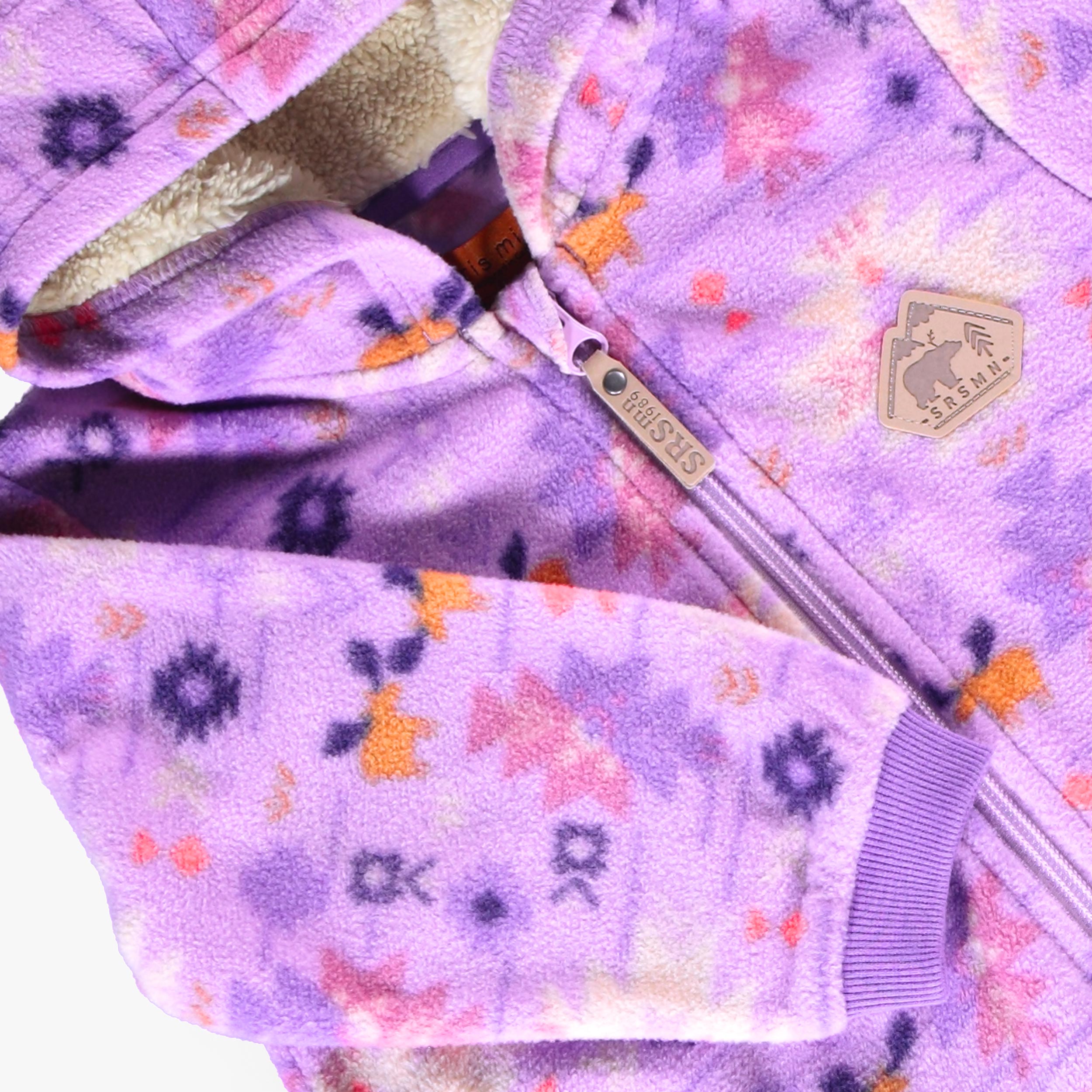 Zoom sur la fermeture éclair, la doublure en sherpa et le capuchon de la une-pièce en polar mauve pour bébé.