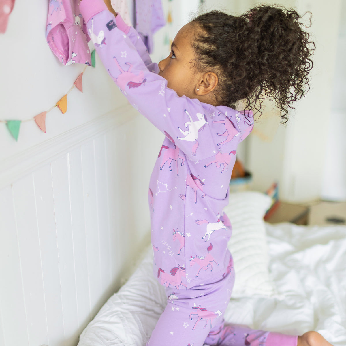 Photo d'un enfant portant le pyjama deux pièces mauve à motifs de licornes, enfant