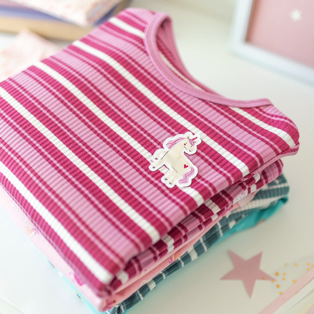 Pyjama deux pièces rose à rayures pour enfant en coton côtelé, plié avec une illustration de licorne brodé