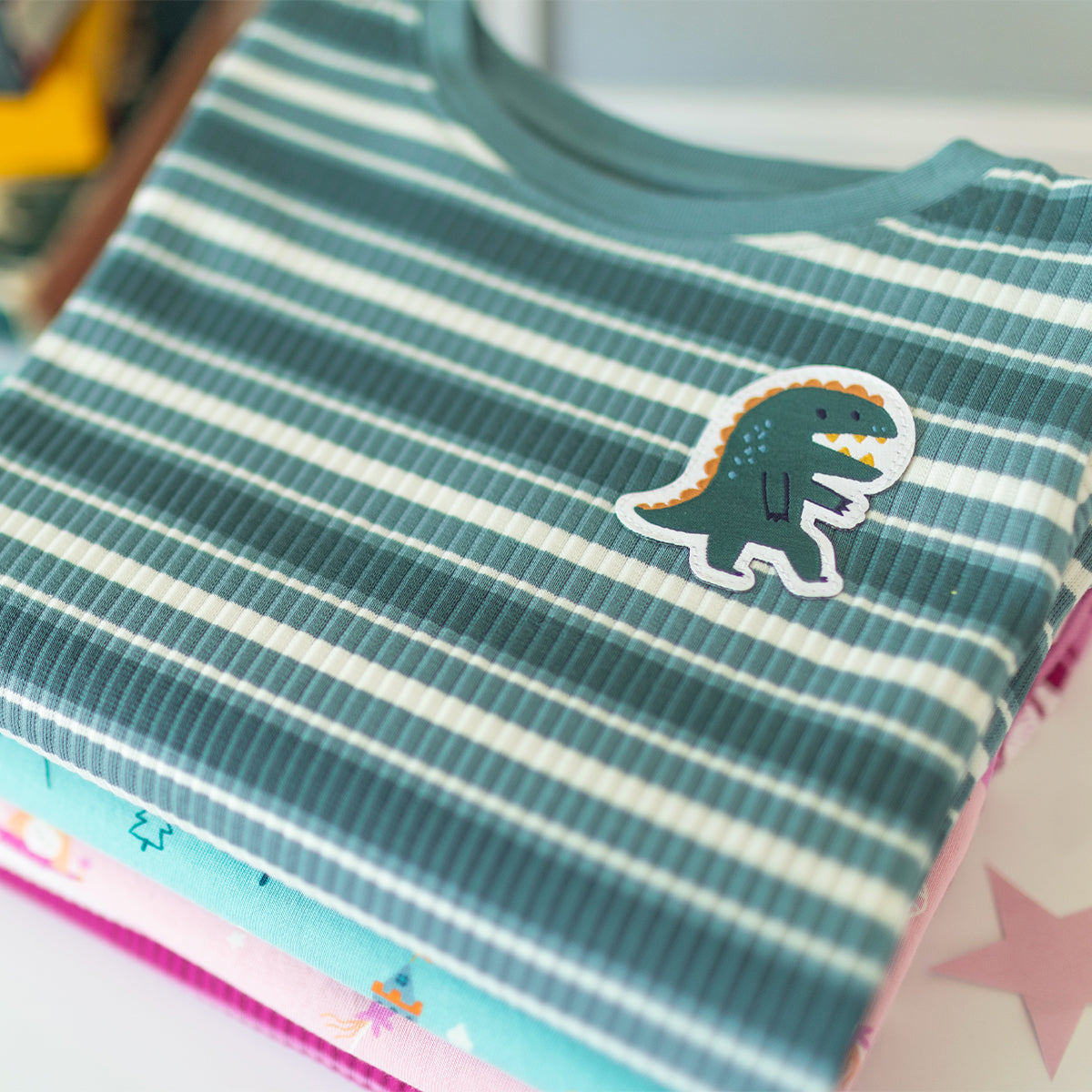 Pyjama deux pièces vert à rayures pour enfant en coton côtelé, plié avec une illustration de dinosaure brodé