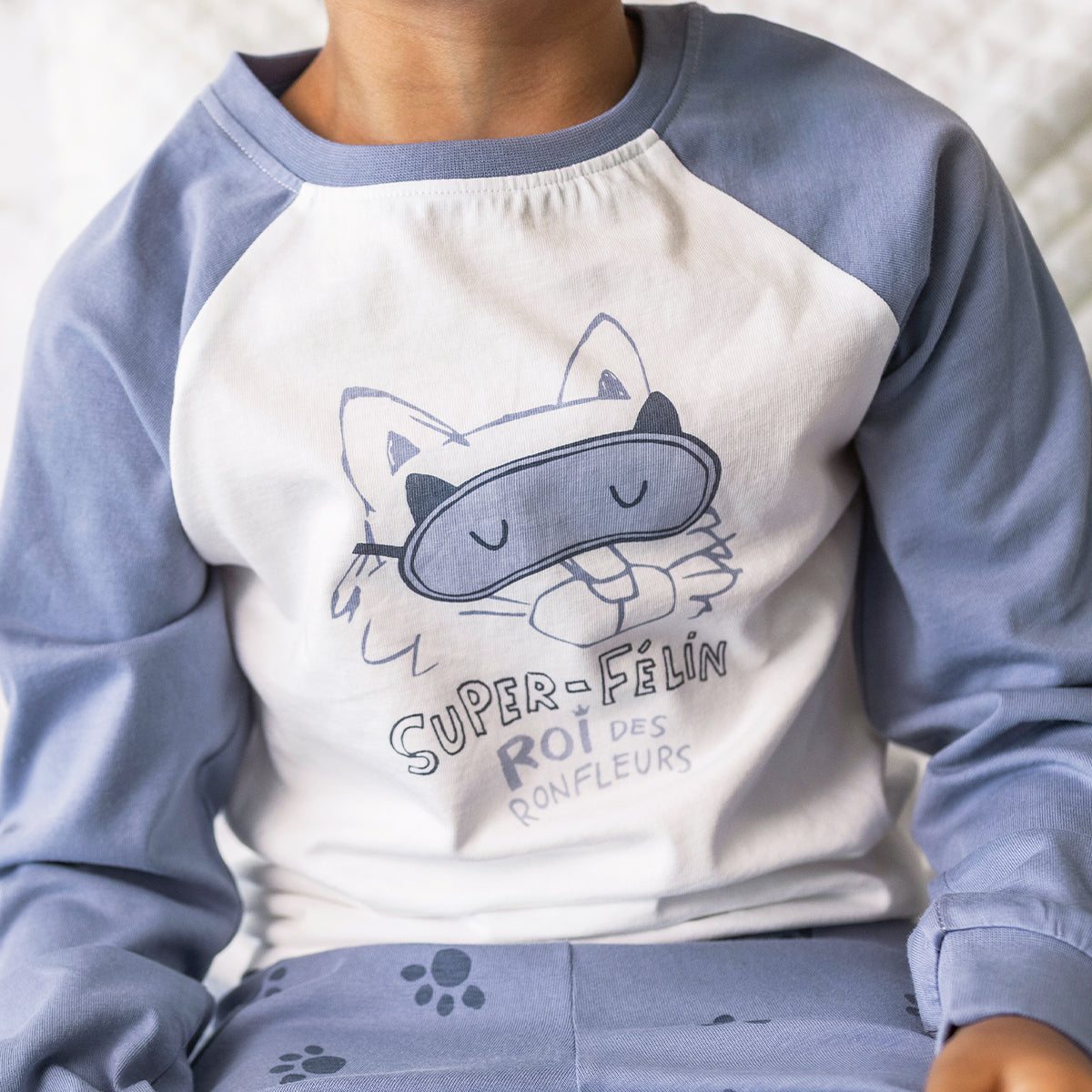 Gros plan du pyjama deux pièces bleu à illustration de chat pour enfant en coton doux, porté par un enfant