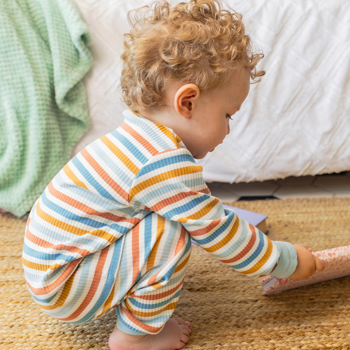 Pyjama deux pièces rayé crème, bleu et orangé pour bébé en coton côtelé, porté par un bébé et orné d'un écusson de chien