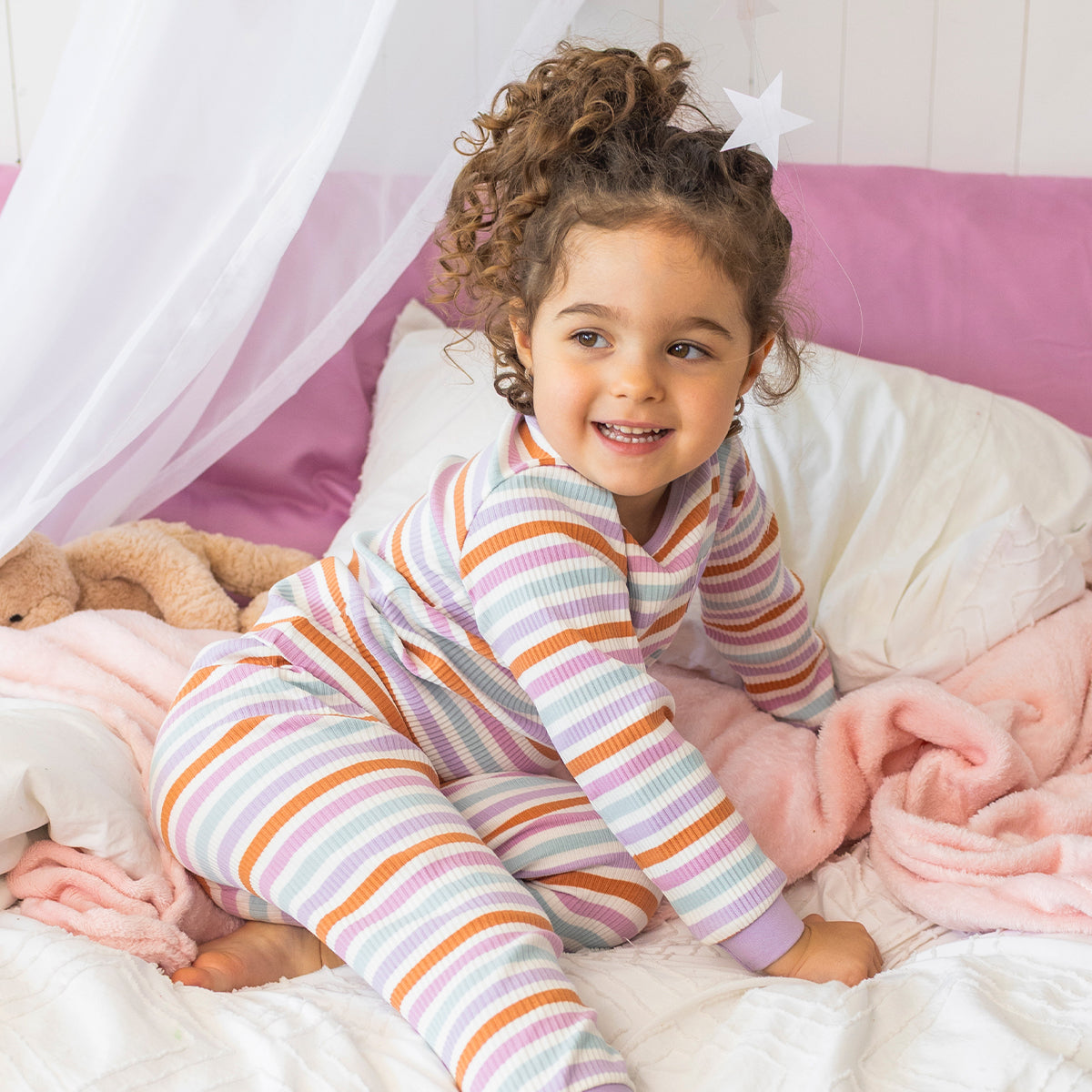 Pyjama deux pièces rayé multicolore pour bébé en coton côtelé, porté par un bébé dans une chambre