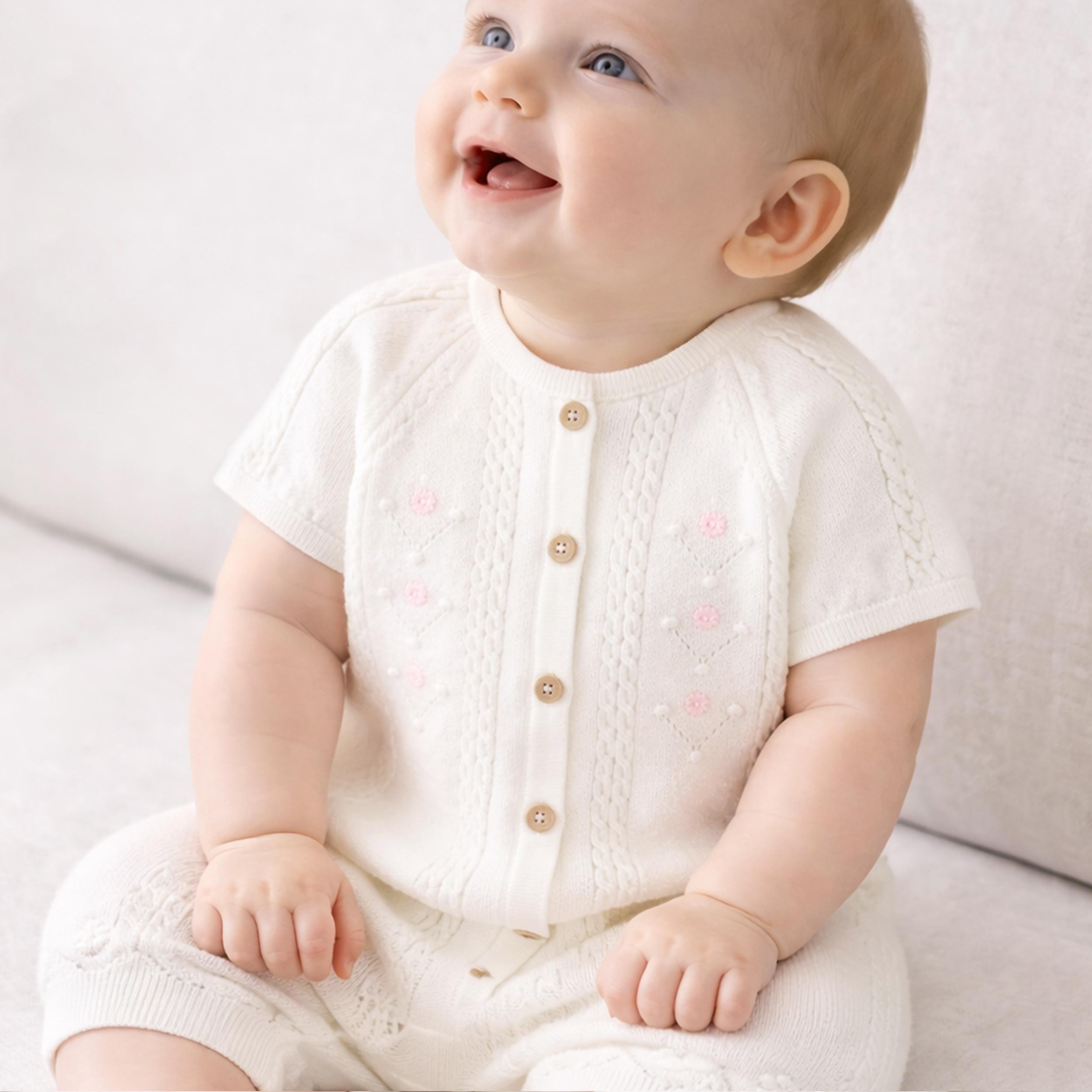 Photo bébé portant de la barboteuse crème en tricot à motif pointelle, naissance