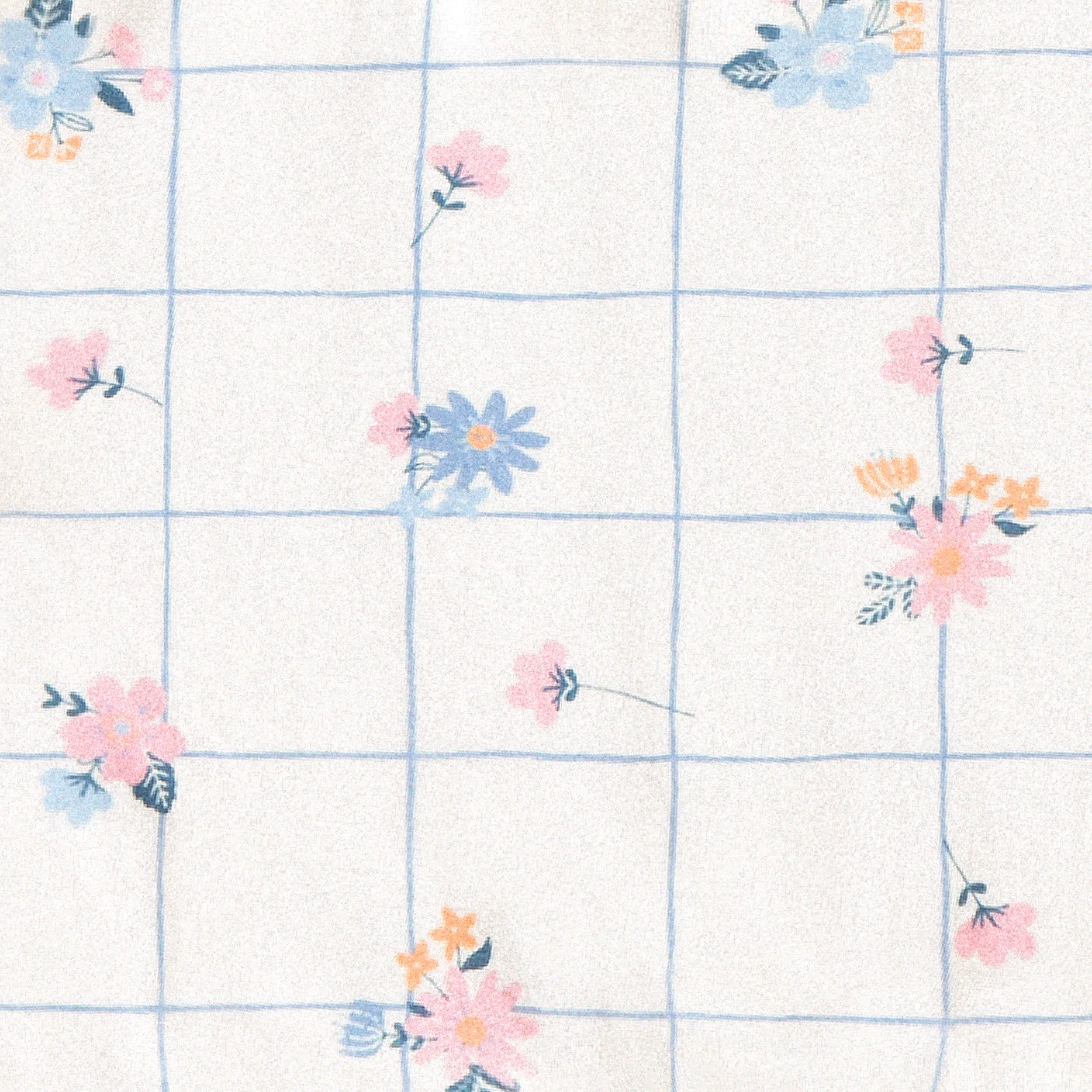 Zoom détails de la barboteuse blanche à carreaux et fleurs, bébé