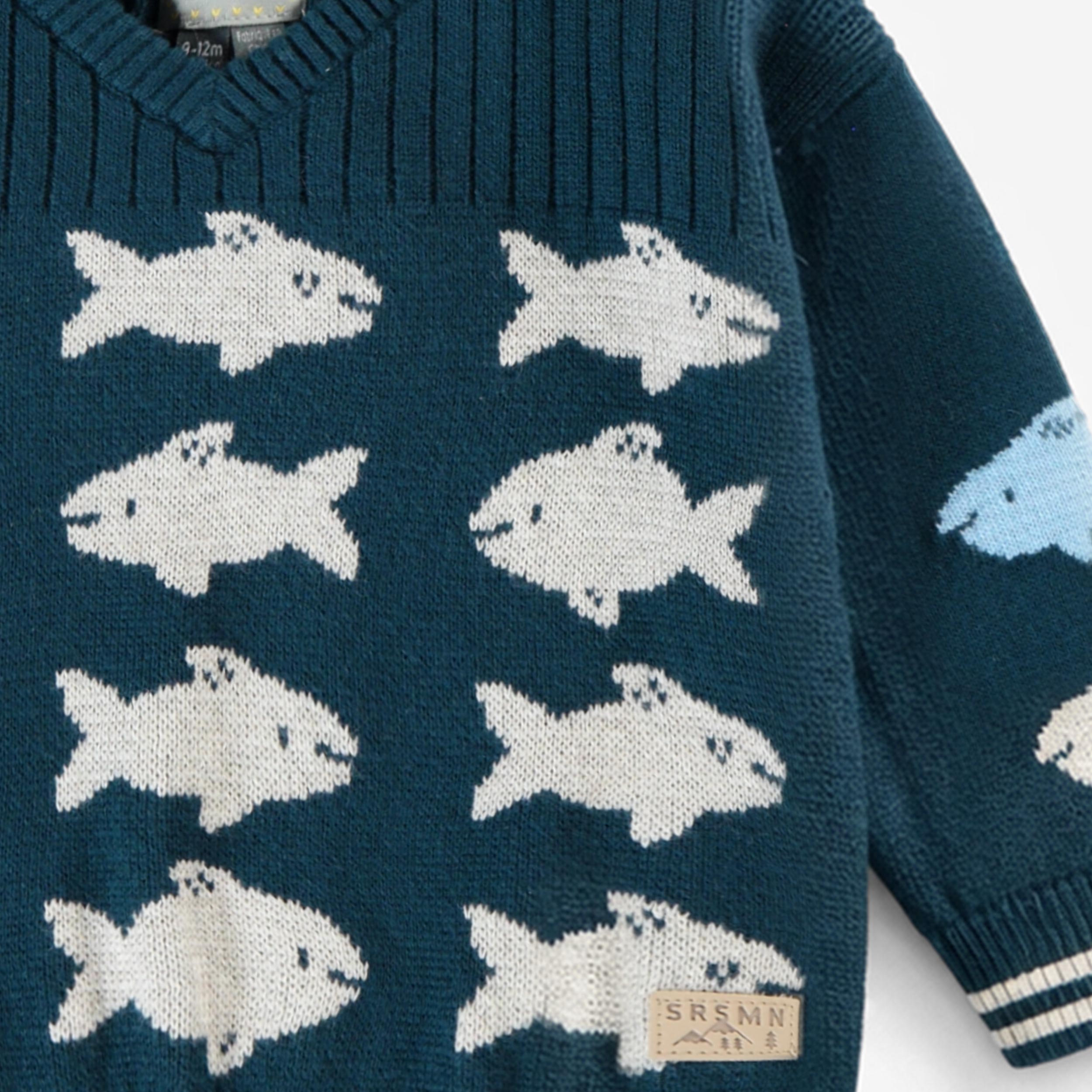 Zoom détails du chandail bleu en tricot avec poissons, bébé