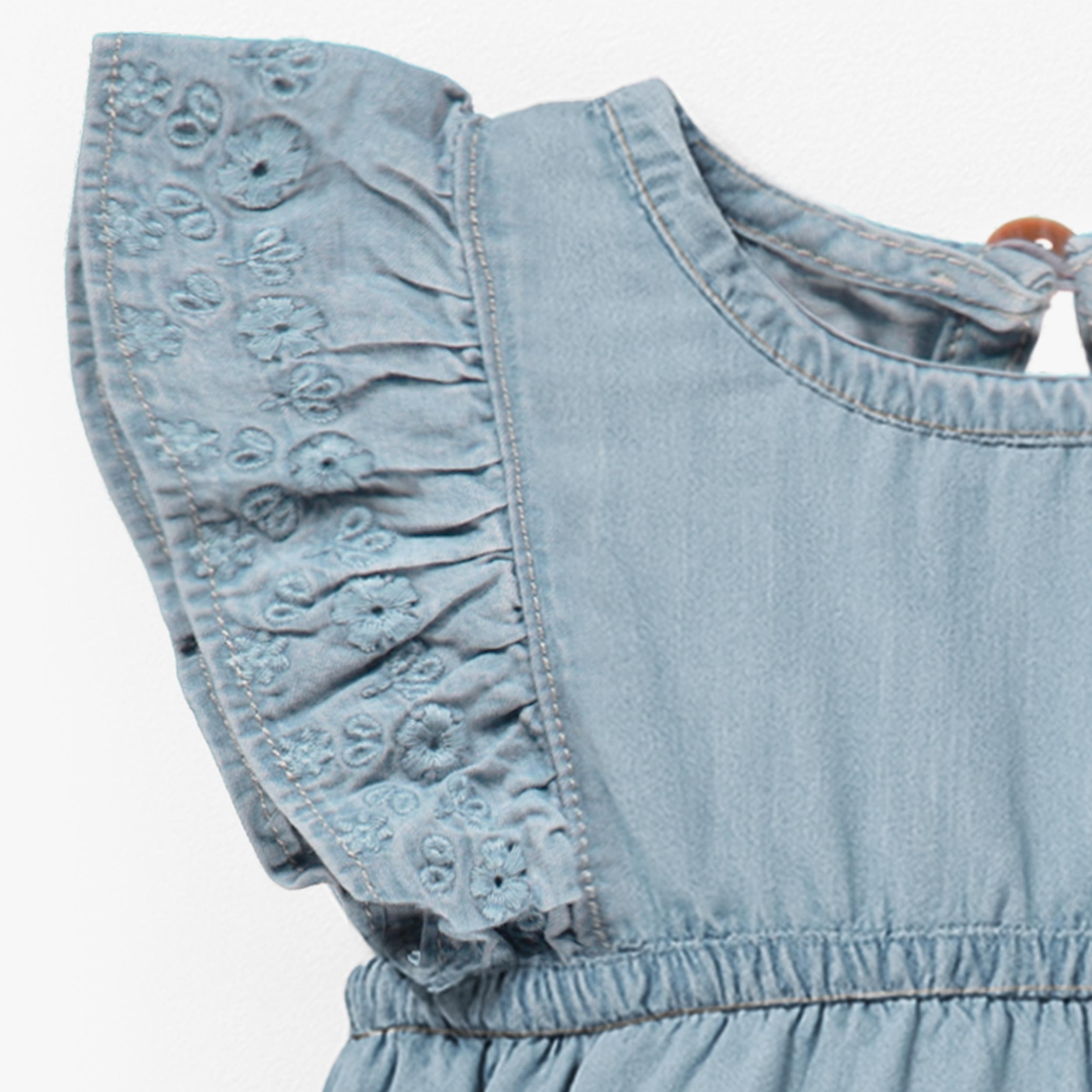 Zoom détails de la barboteuse bleu pâle en denim avec broderie anglaise, naissance