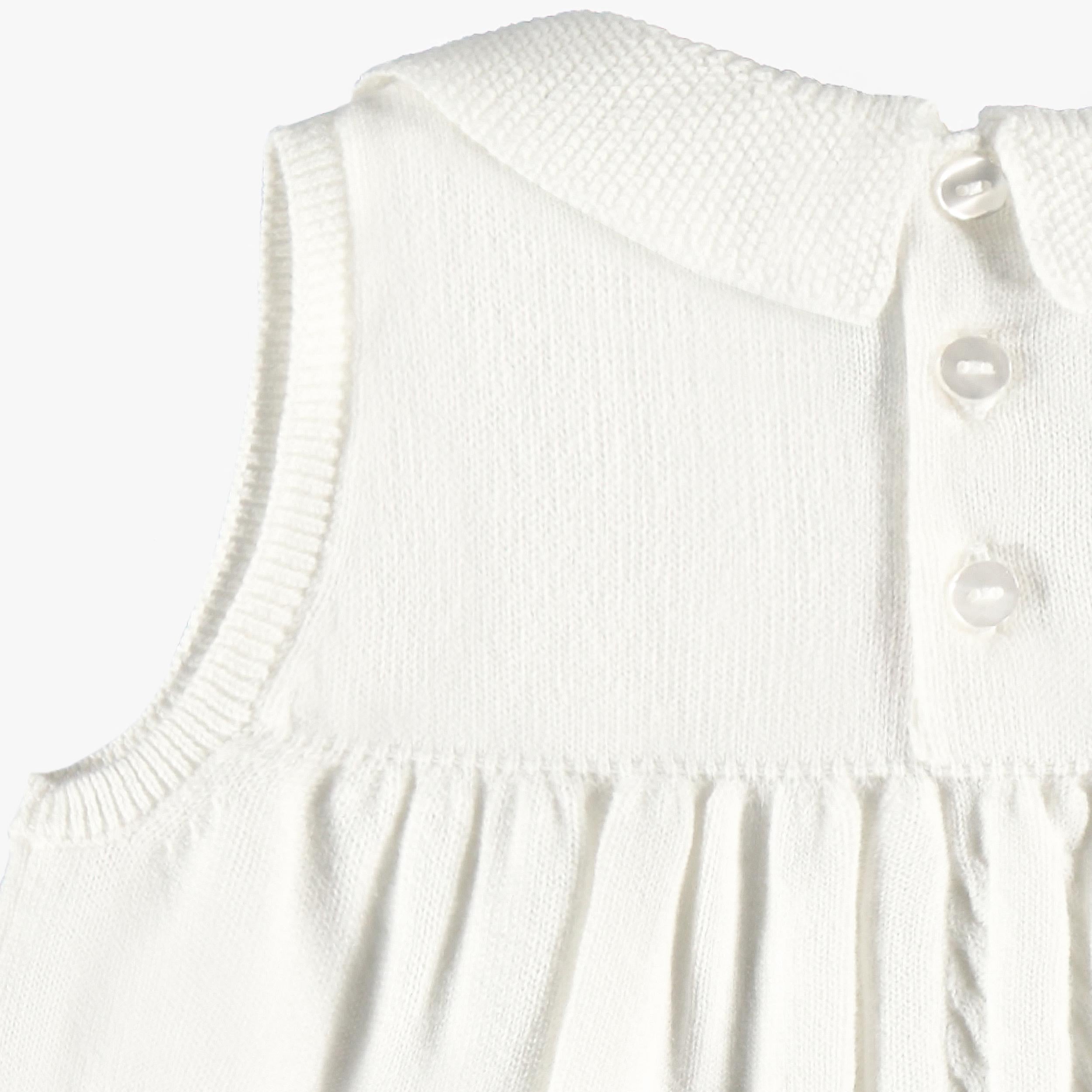 Détails des boutons dos de la robe blanche en tricot avec broderies de fleurs, bébé