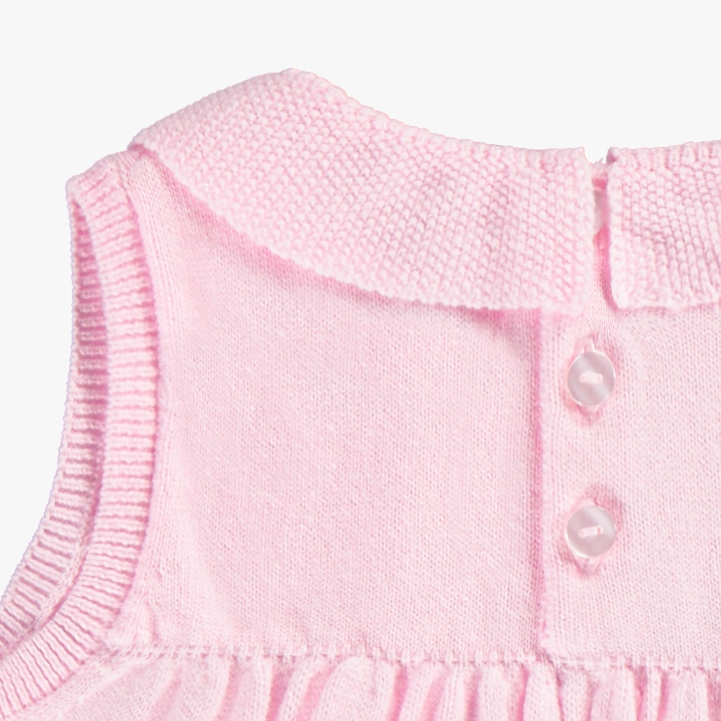 Zoom des boutons au dos de la dos de la robe rose en tricot, bébé