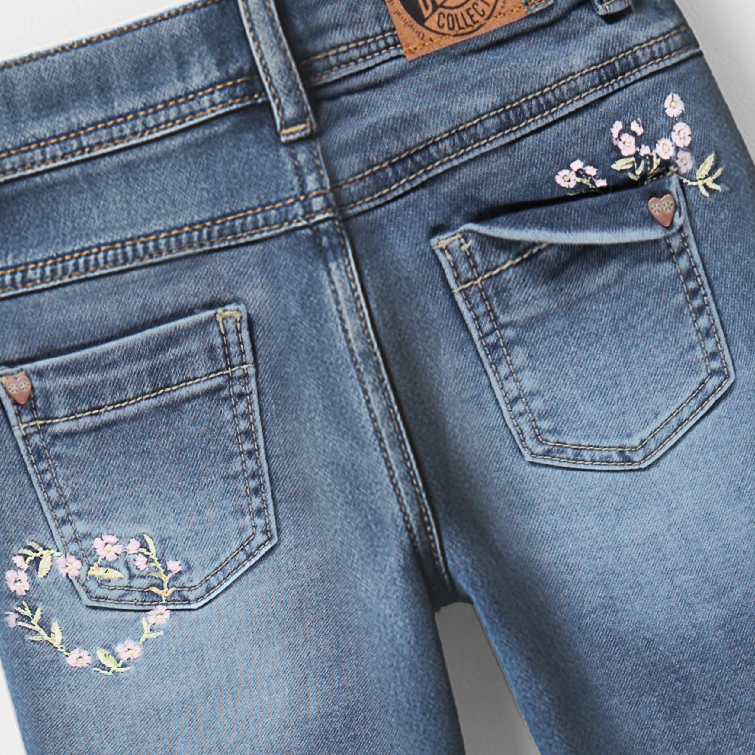 Zoom détails dos du jean bleu avec broderie florale, enfant 