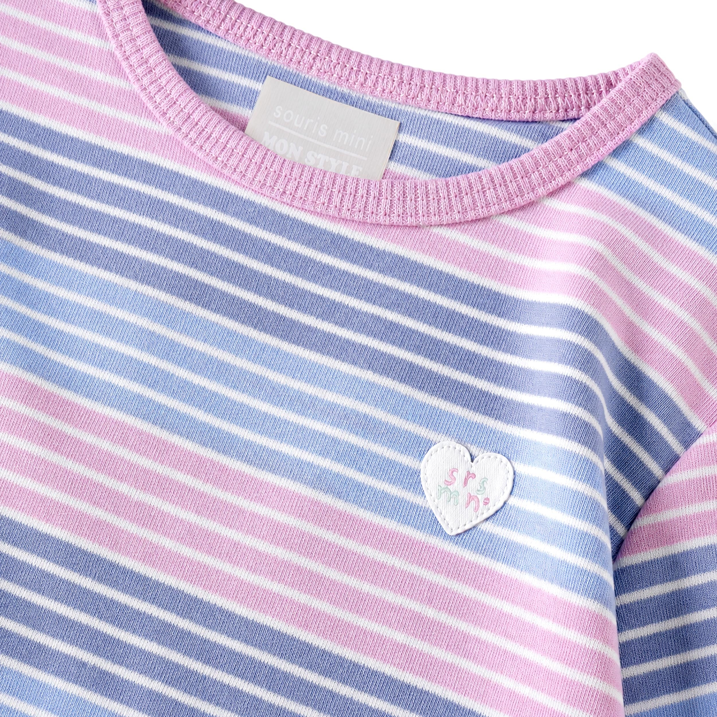 Gros plan sur un chandail à manches longues pour bébé fille à rayures bleu pâle, bleu et rose avec encolure rose et écusson cœur décoratif.