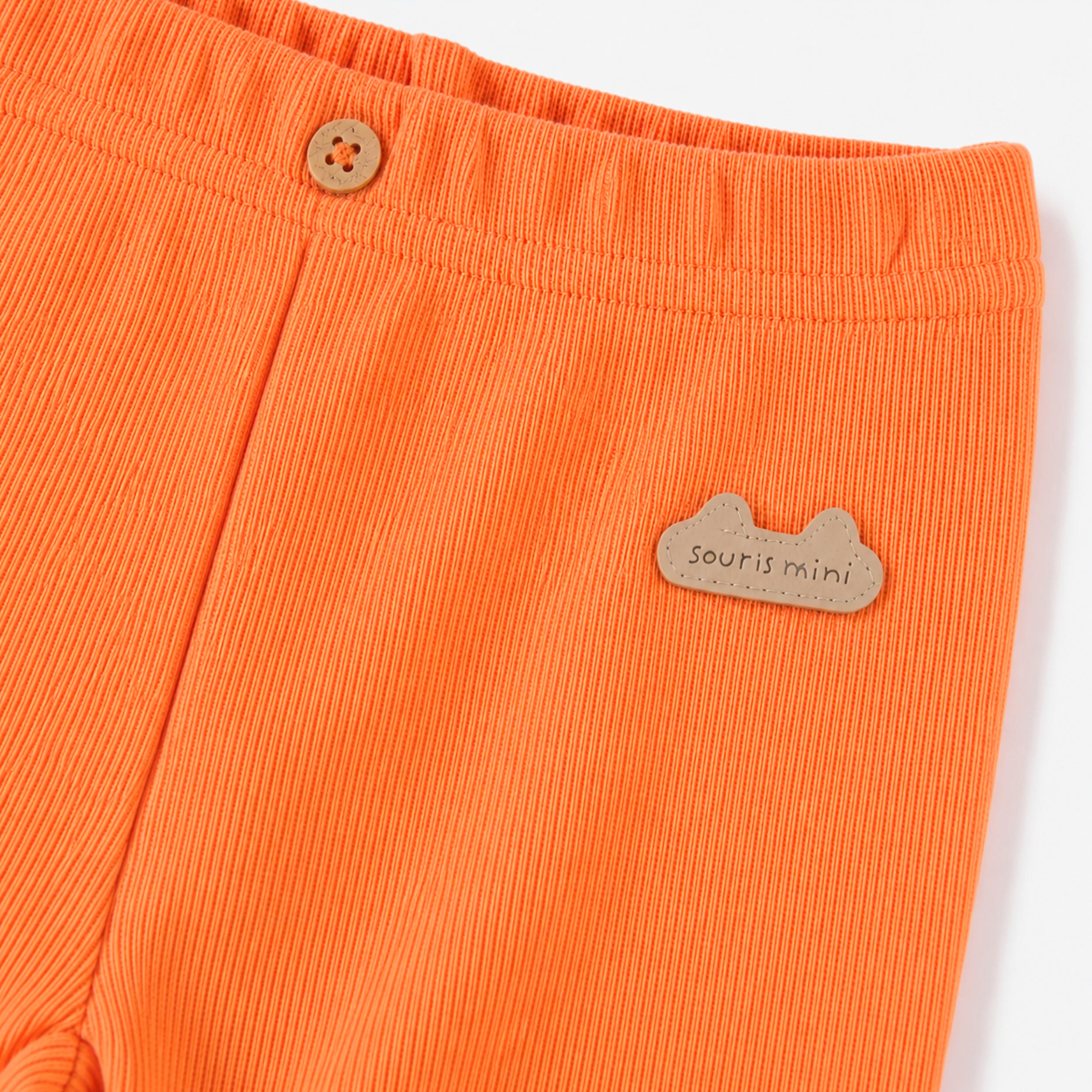 Gros plan du legging côtelé corail orangé, layette