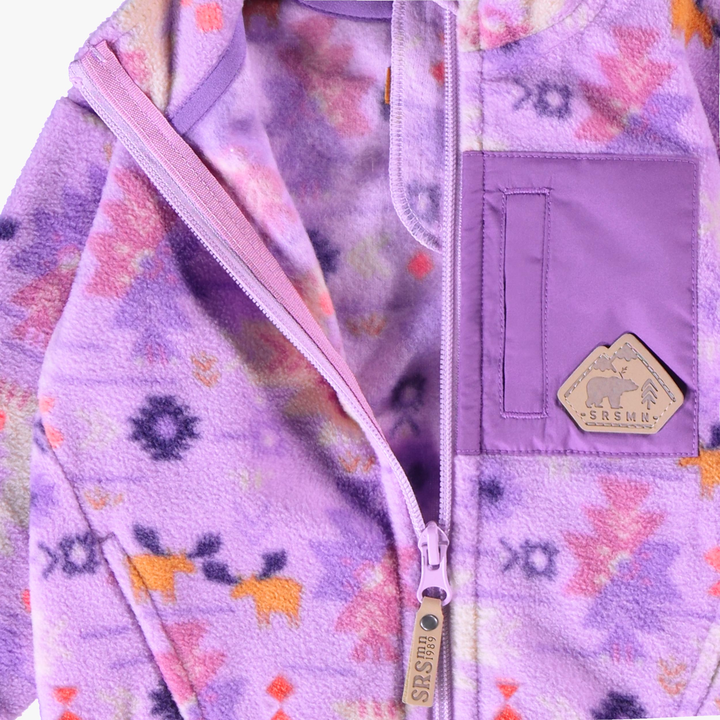 Détail de la doublure en polar, de la fermeture éclair et de la poche de la veste mauve à motifs pour bébé.