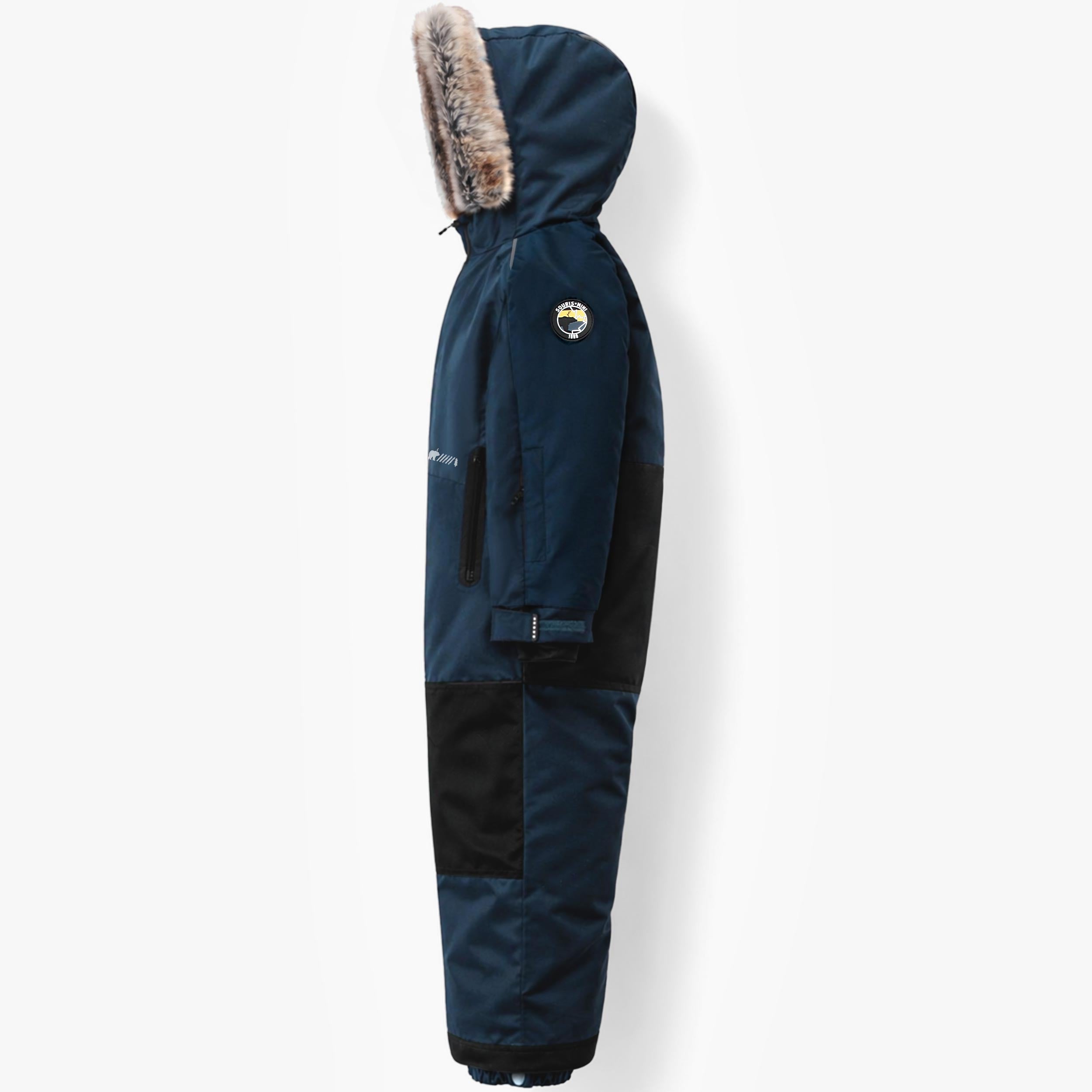 Profil gauche d’un habit de neige une pièce pour enfant bleu marine, avec capuchon isolé, bordure en fausse fourrure et renforts résistants aux genoux.
