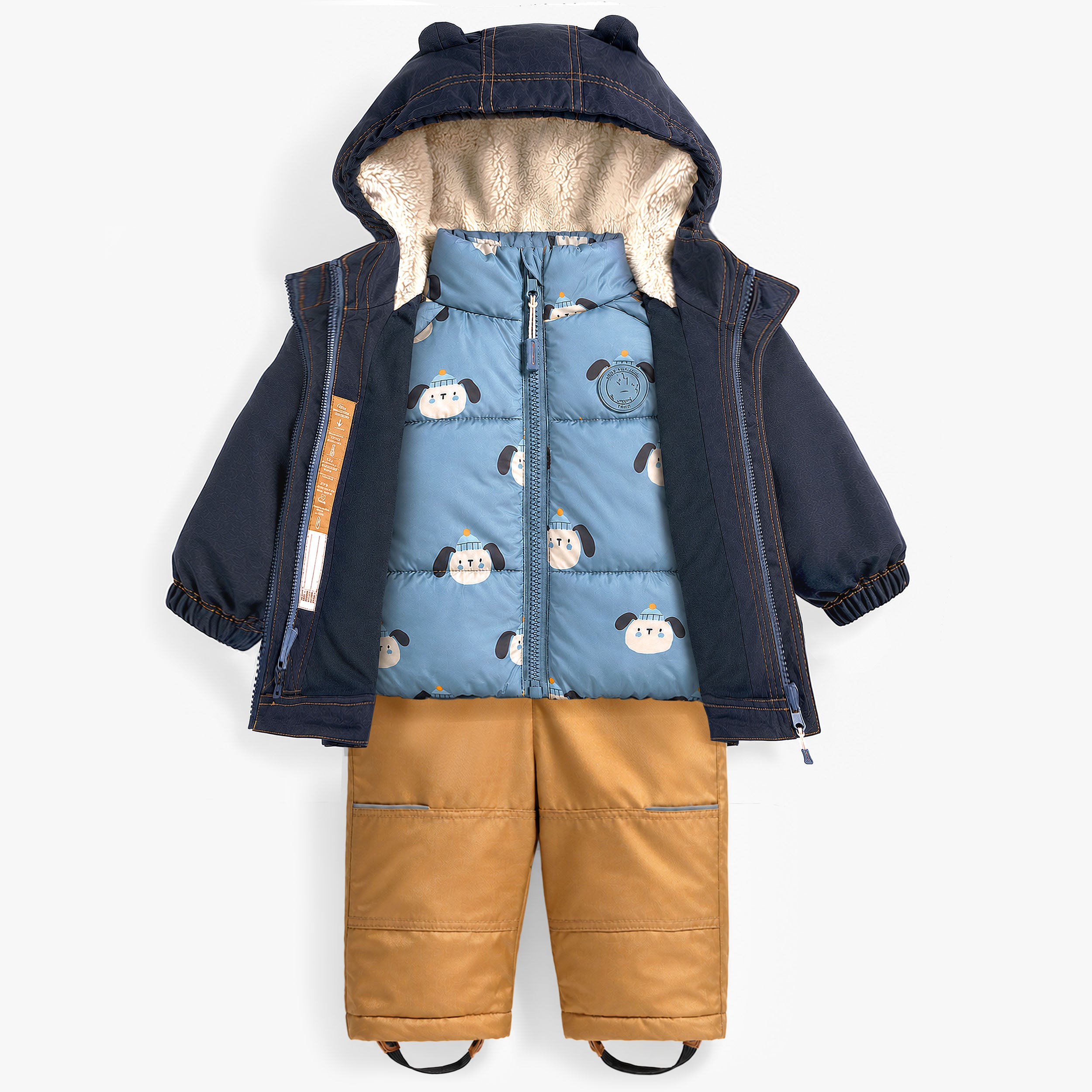 Ensemble de neige pour enfant avec manteau bleu marine ouvert révélant une doudoune amovible bleue à motif ludique et un pantalon isolé camel.