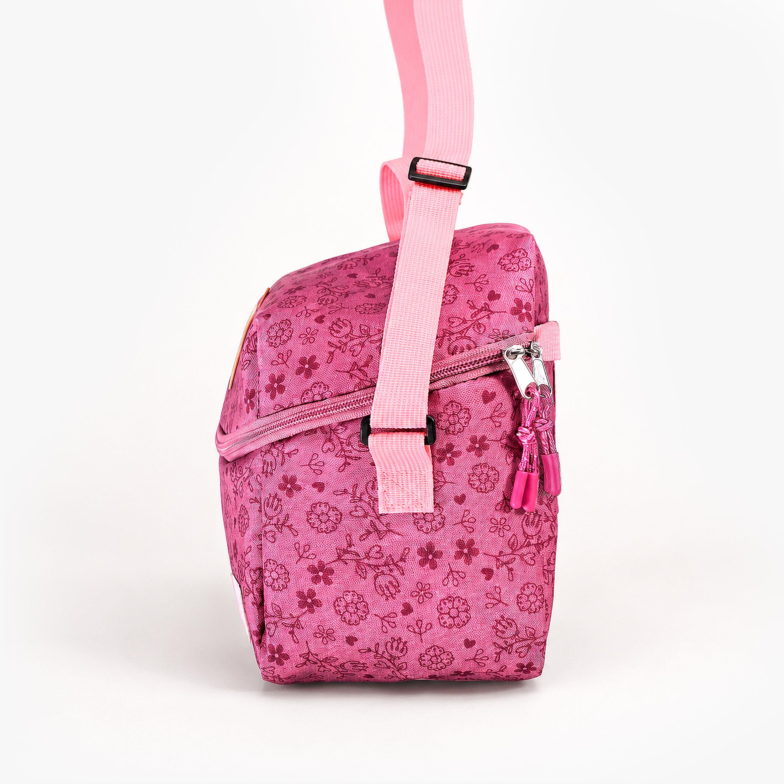 Vue de profil d’un sac isotherme enfant rose à imprimé floral avec bandoulière réglable et fermeture zippée.