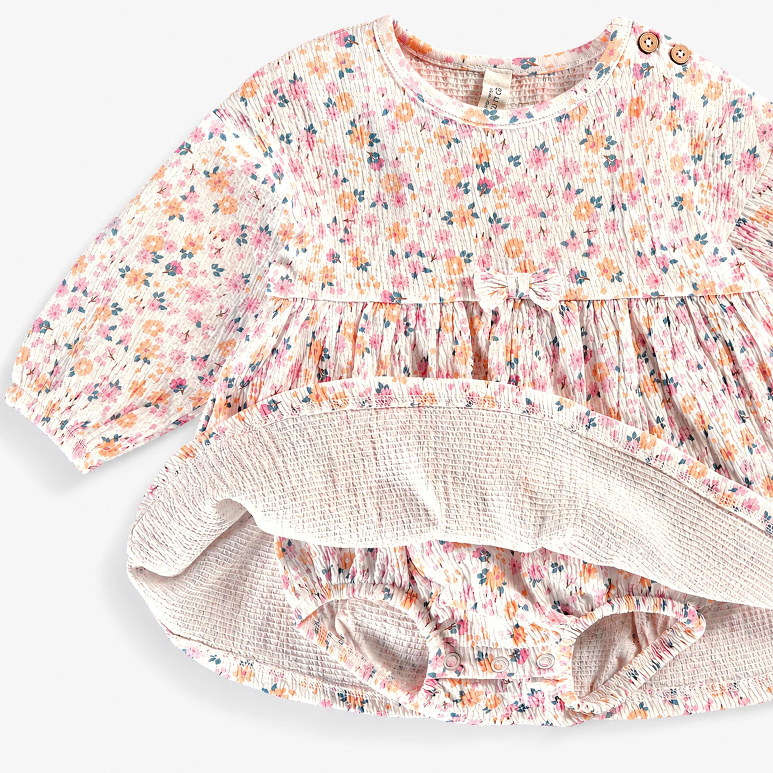 Robe bébé fille à manches longues avec imprimé floral multicolore, présentée ouverte pour montrer le body intégré avec fermeture à pressions.