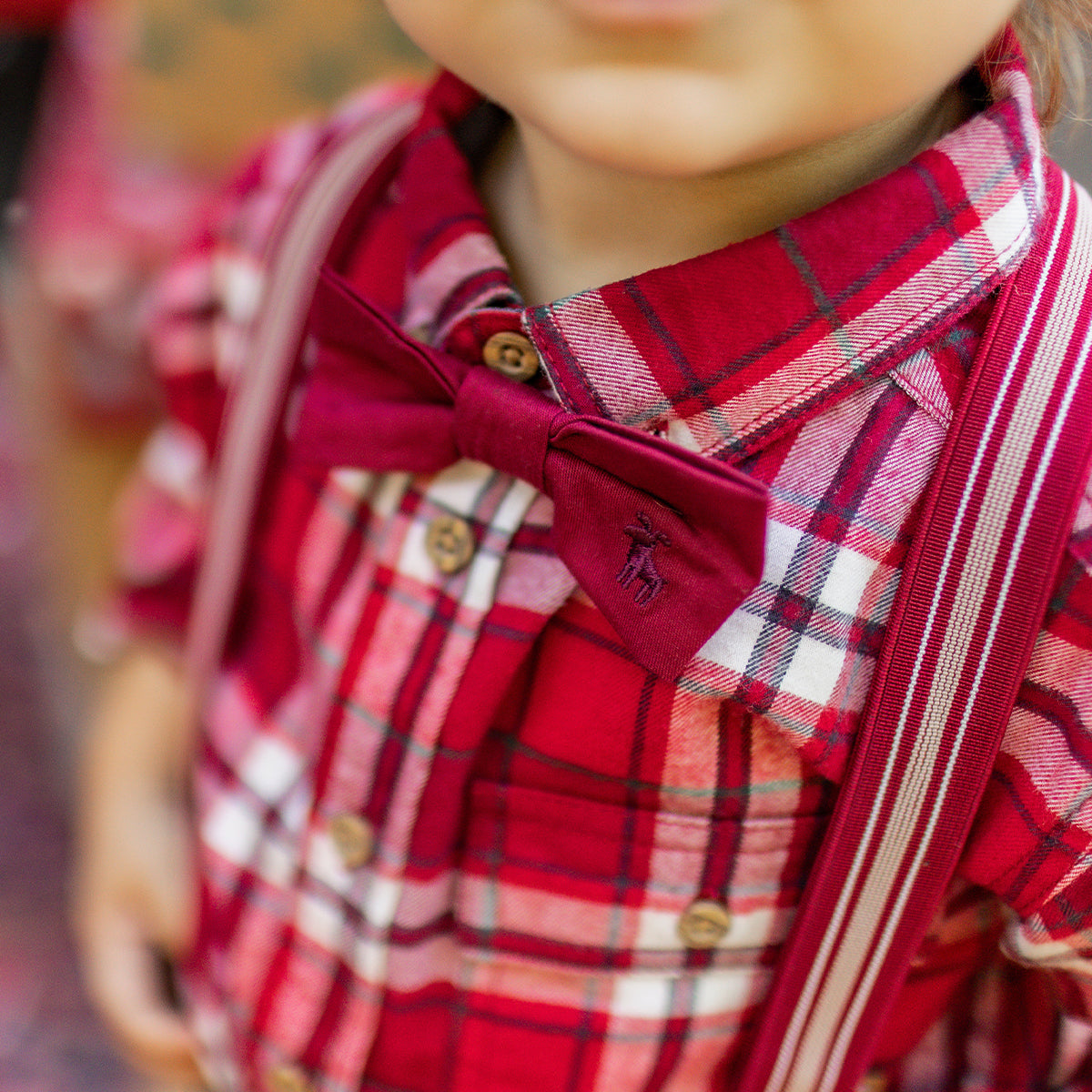 Gros plan sur un t-shirt rouge pour enfant avec imprimé d’ours de Noël et guirlande lumineuse, porté sous une chemise à carreaux, collection Souris Mini.