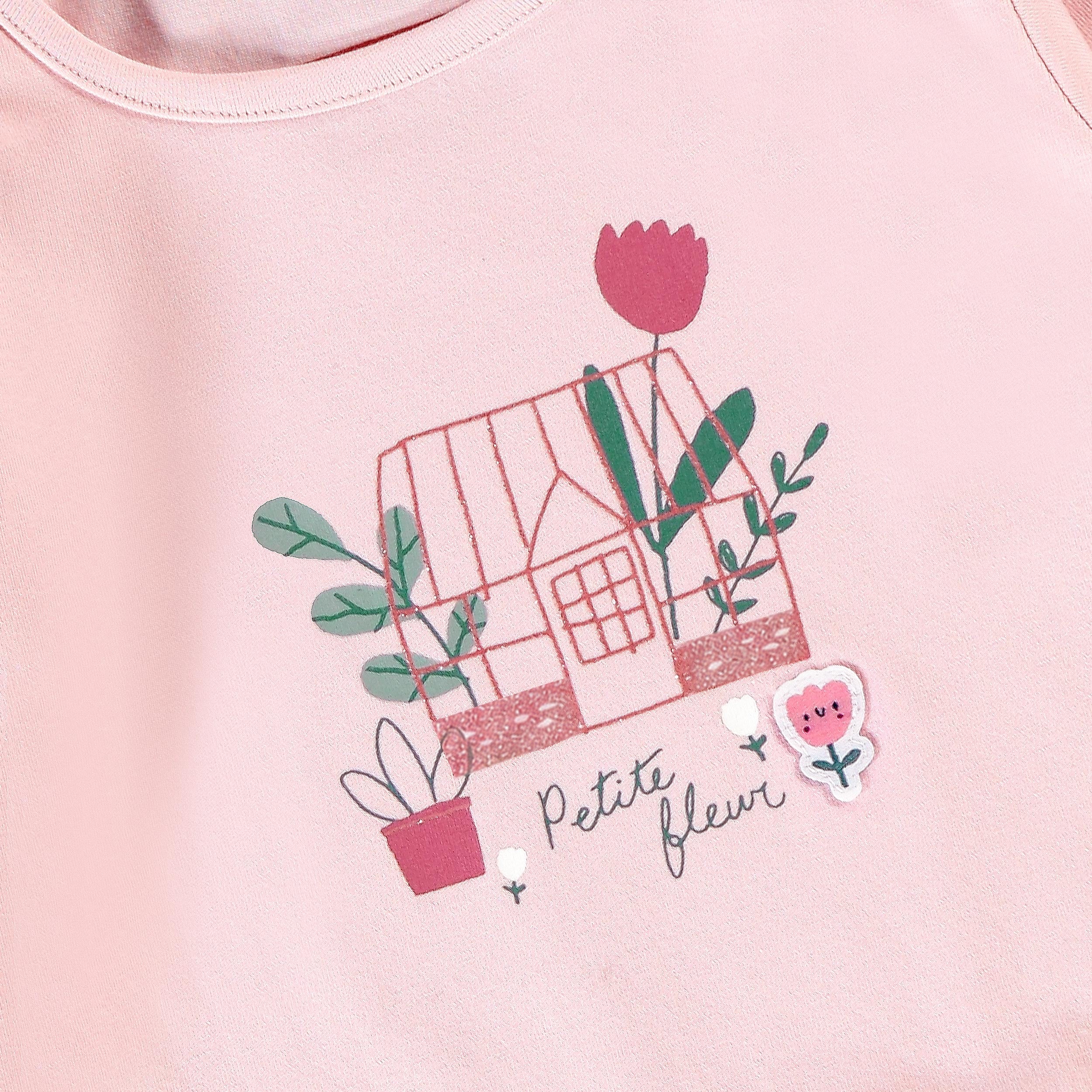 Détail de la tunique bébé rose avec illustration maison fleurie et motif floral
