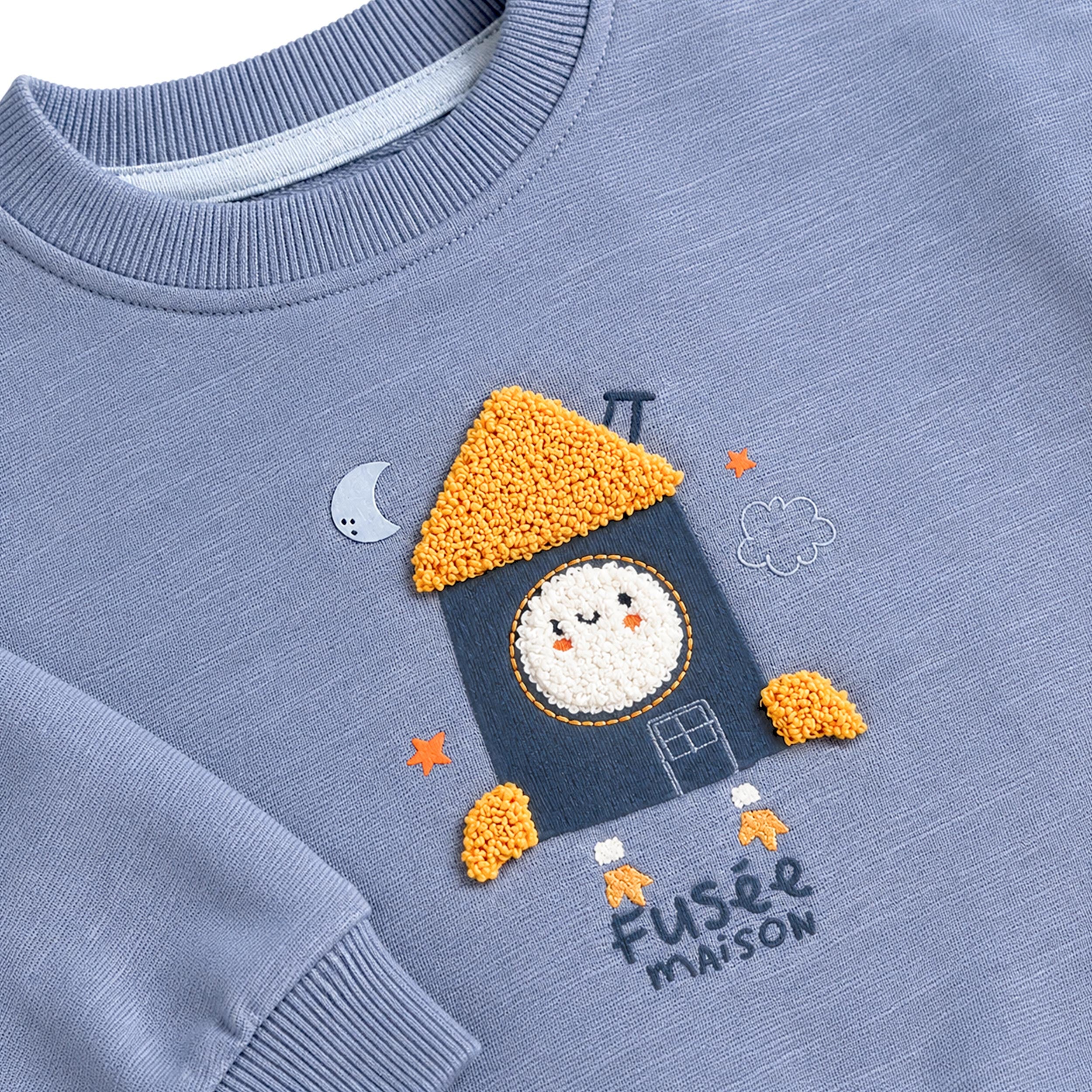 Zoom sur motif fusée maison texturé sur sweat bébé bleu pastel 