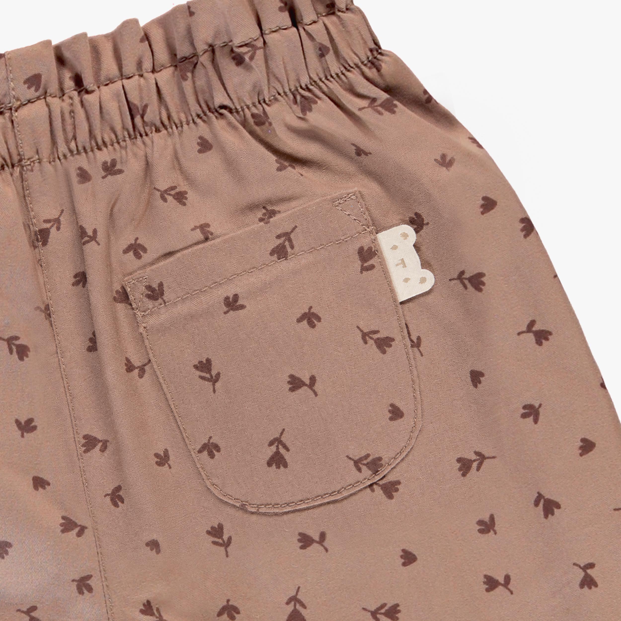Zoom sur la poche arrière d’un pantalon bébé rose poudré à motif floral avec taille élastique