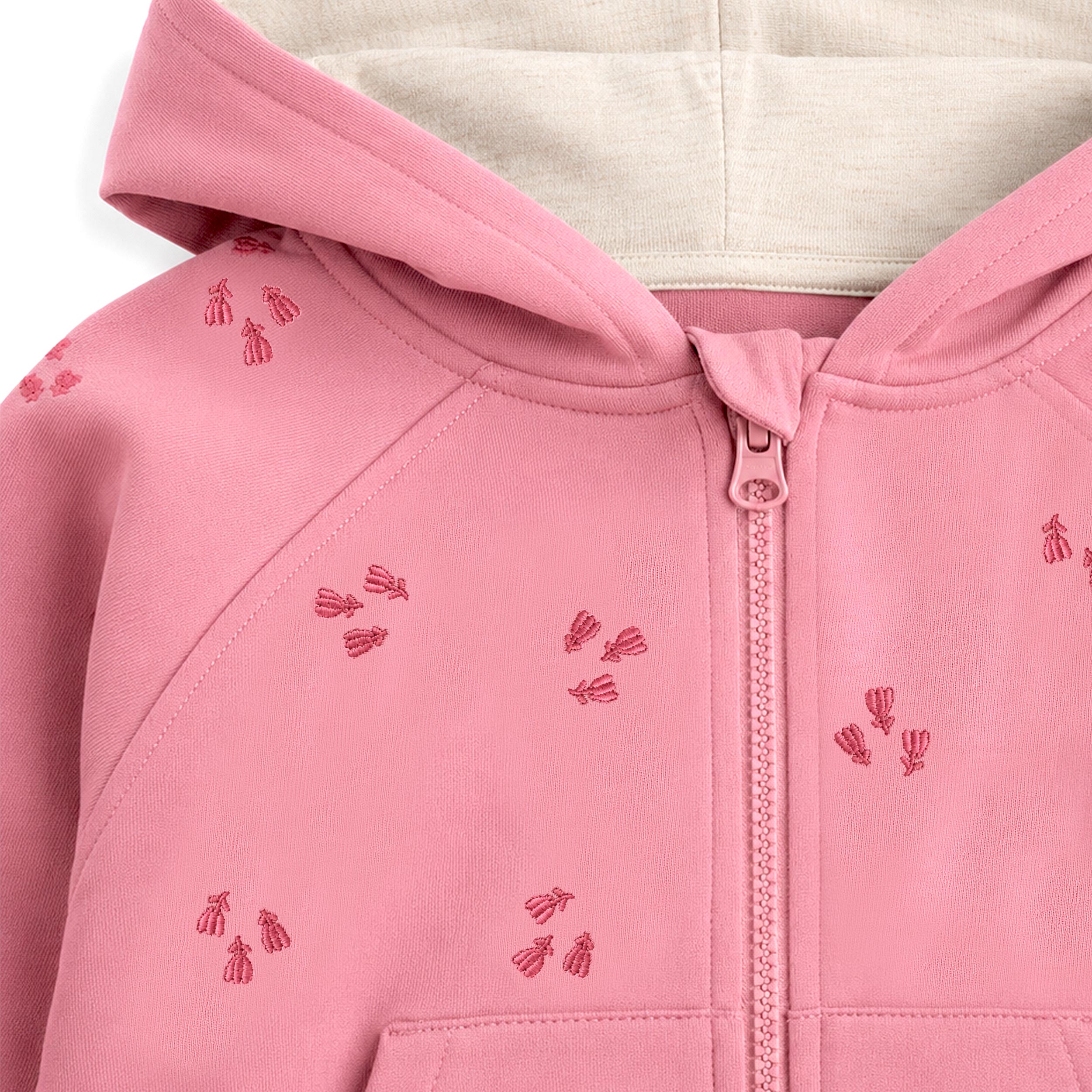 Zoom sur la veste à capuche rose bébé avec fermeture éclair et motifs brodés