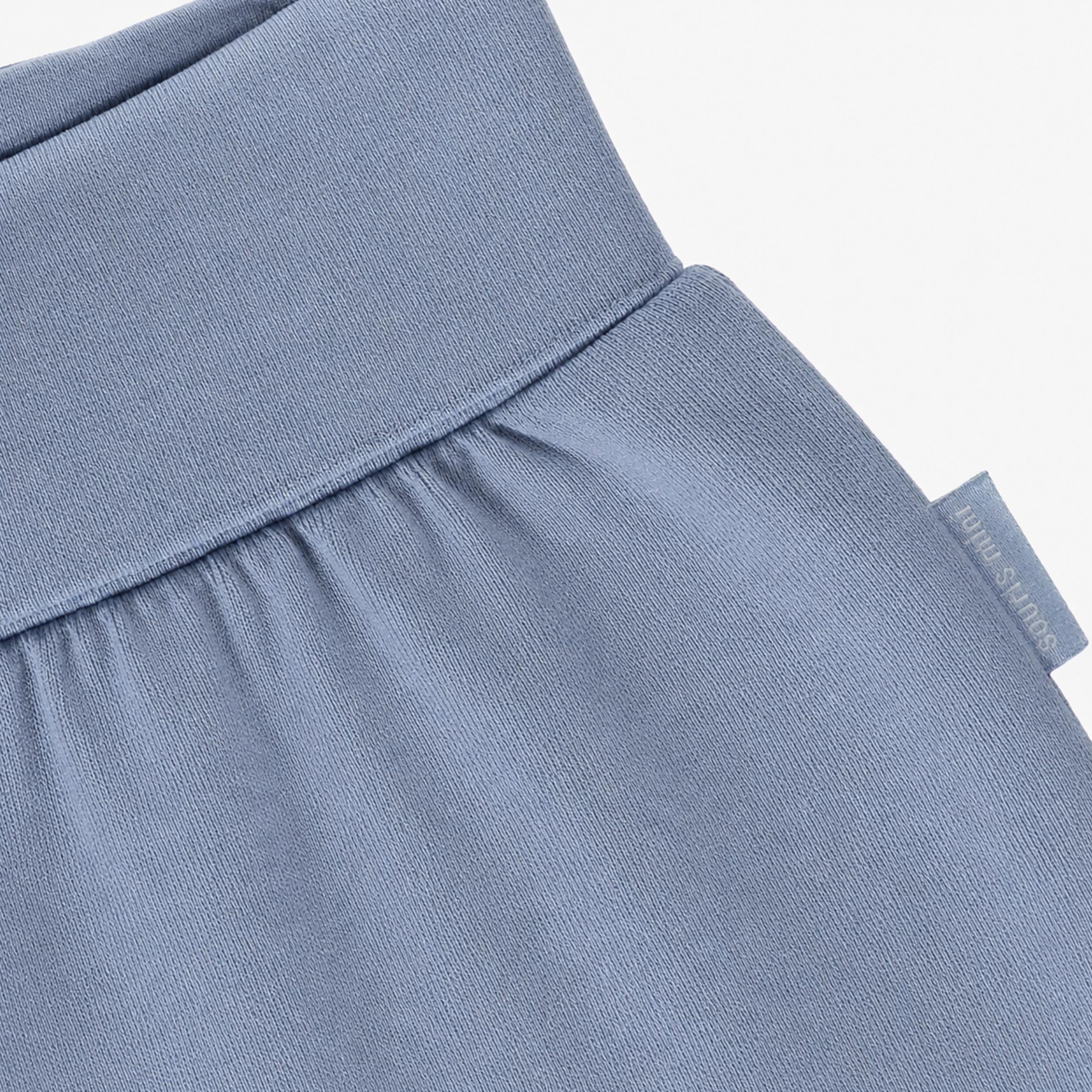 Gros plan de la taille repliable du pantalon bébé bleu en coton.
