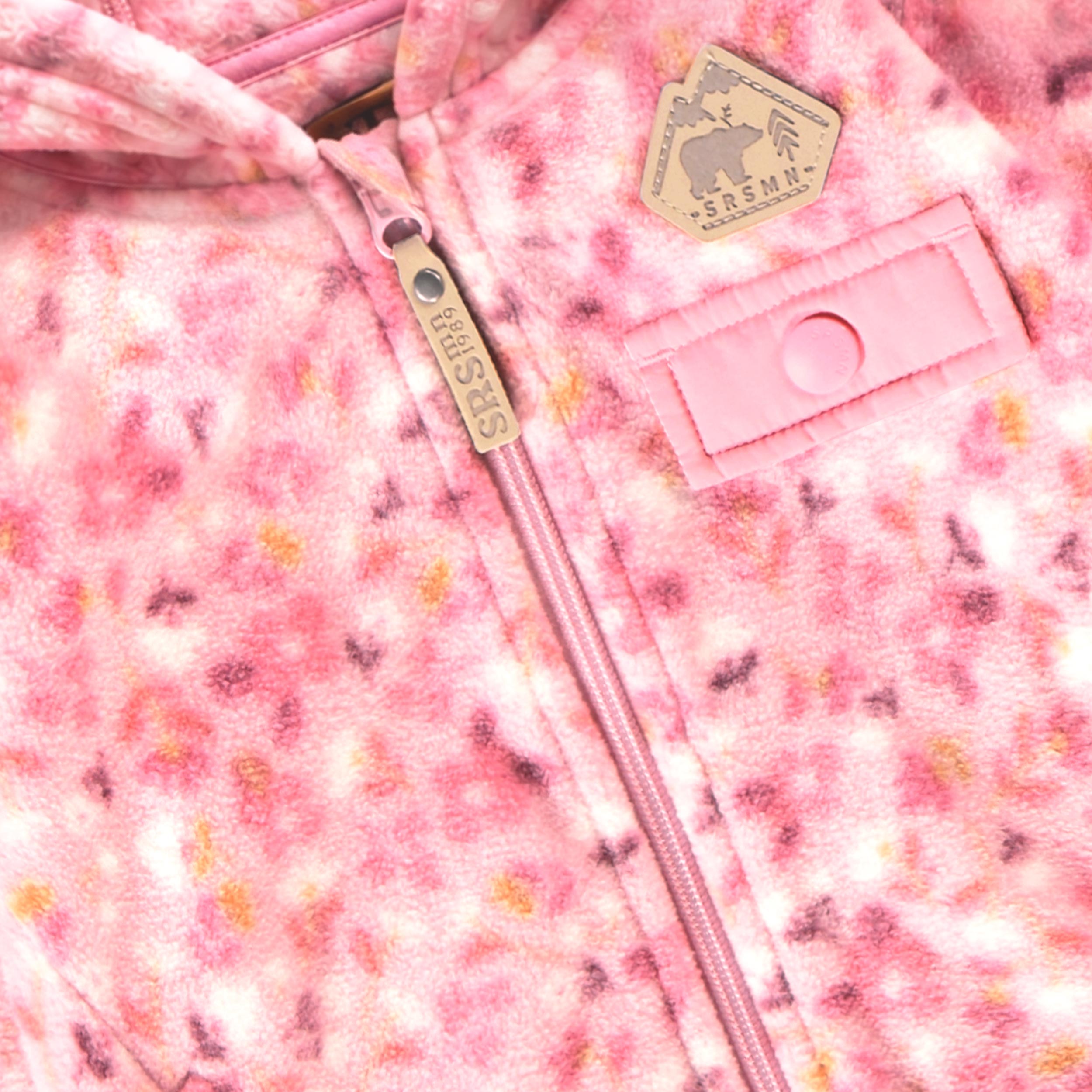 Zoom sur le tissu en polar, la fermeture éclair et le porte-mitaine de la veste rose à imprimé floral pour bébé.